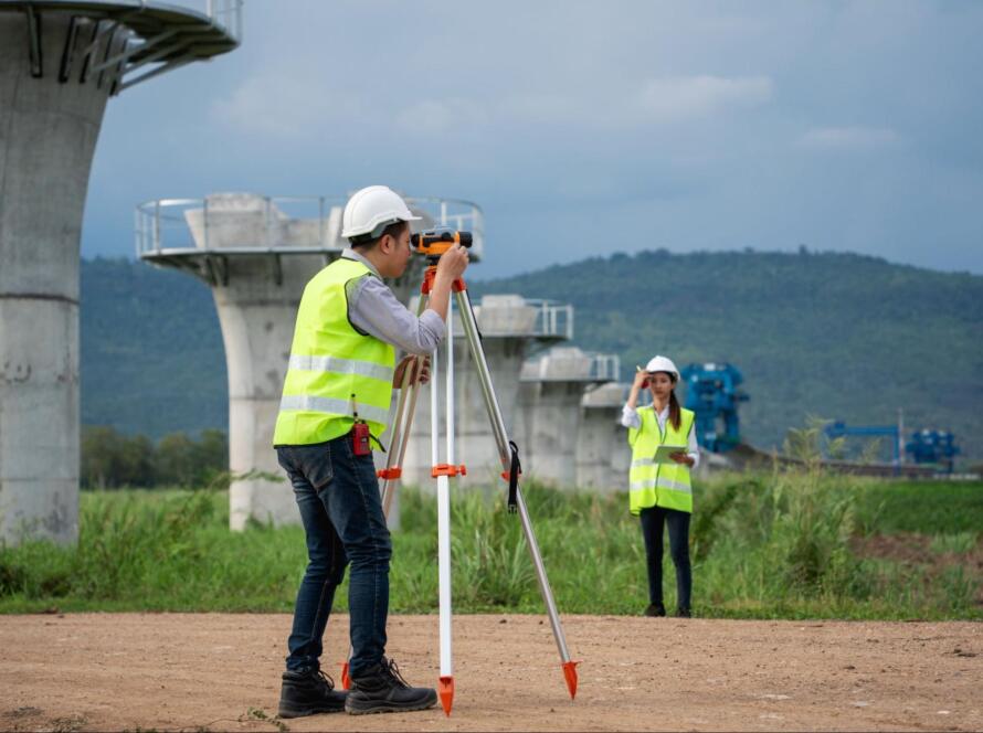People taking measurements with surveying tools, providing licensed land surveying services