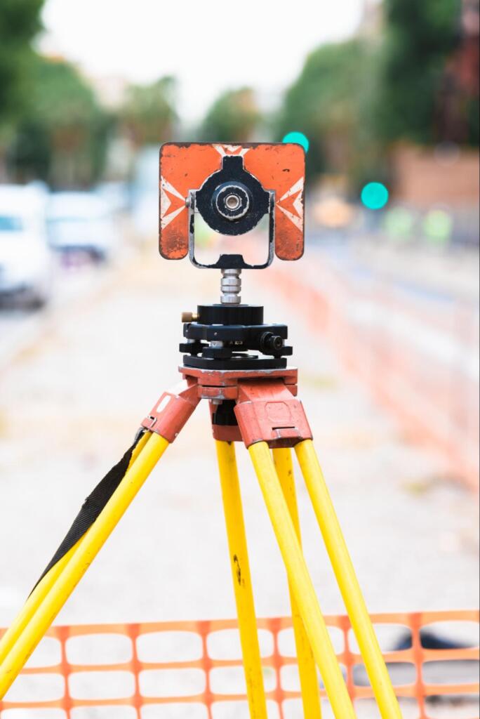 Early-stage land surveying equipment on tripod set up along a street for accurate boundary and construction measurements