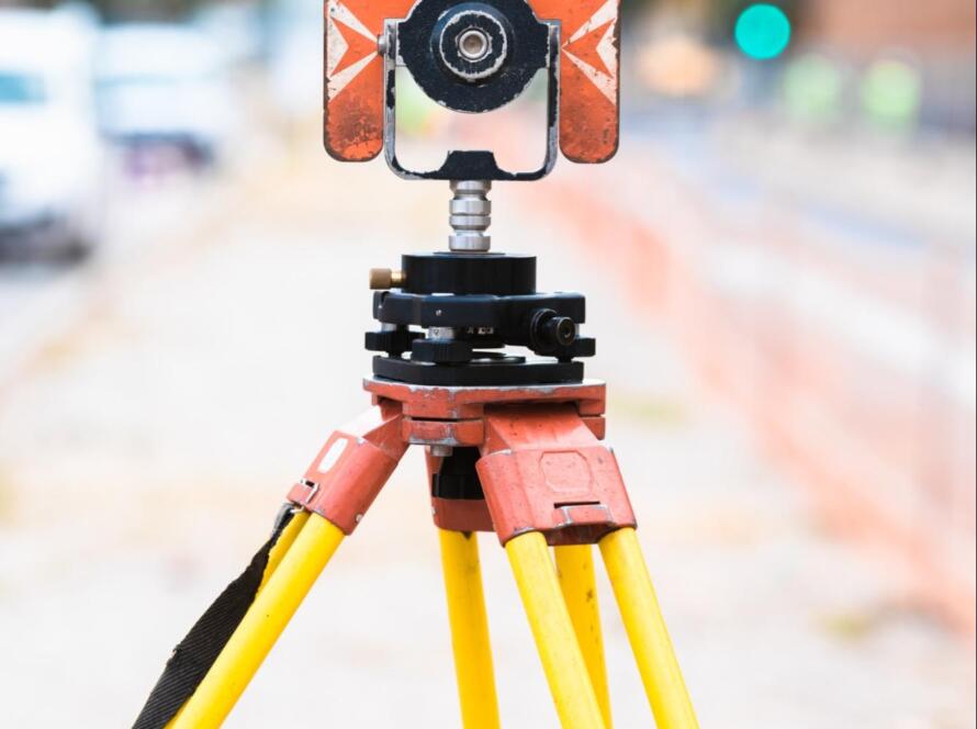 Early-stage land surveying equipment on tripod set up along a street for accurate boundary and construction measurements