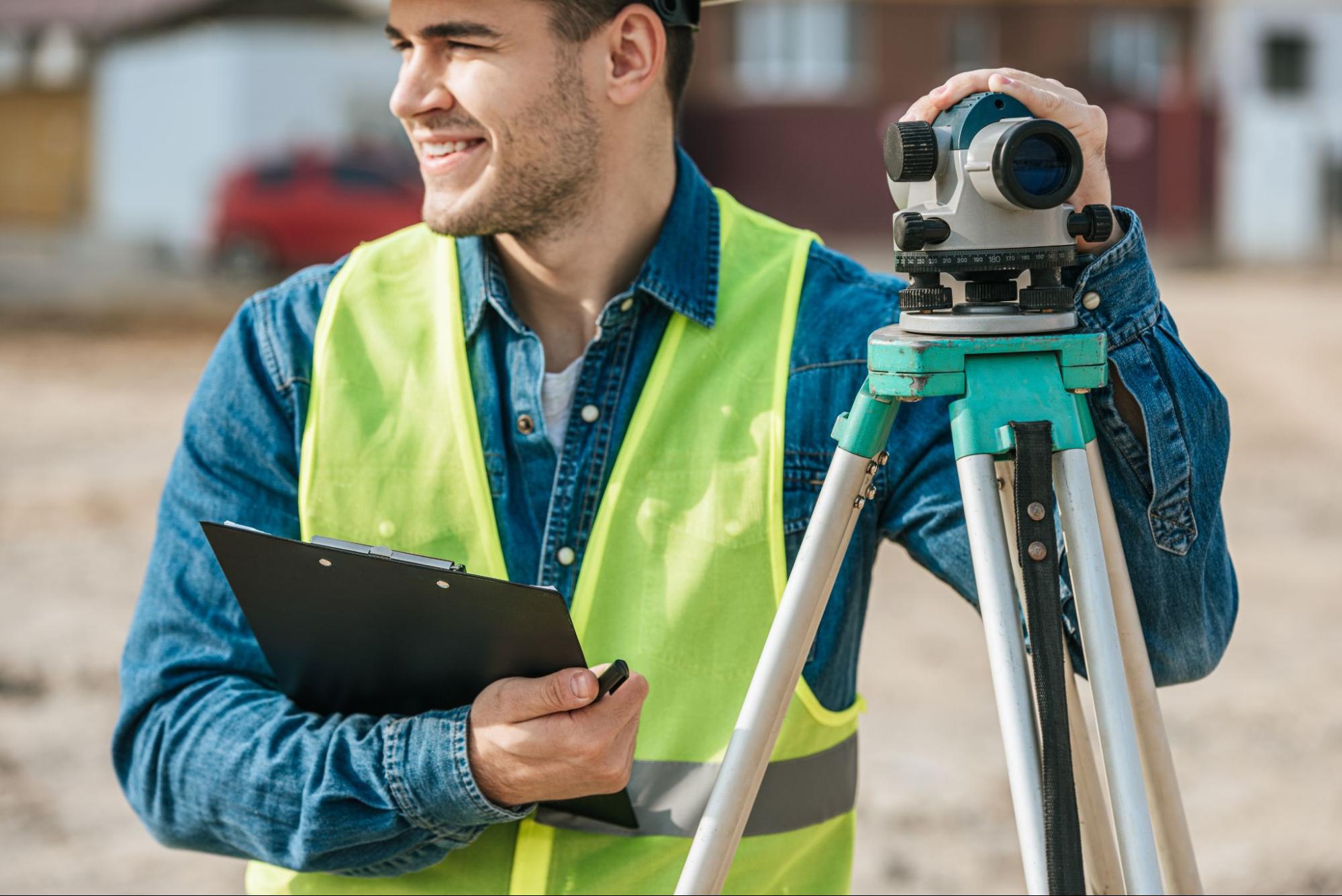 land surveyor using a digital level and clipboard during fieldwork