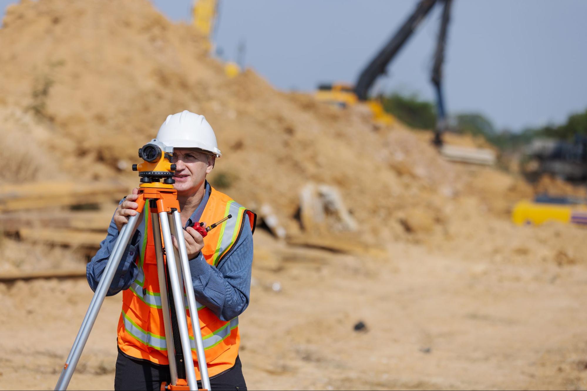 land surveyor using a theodolite on a tripod in a field 
