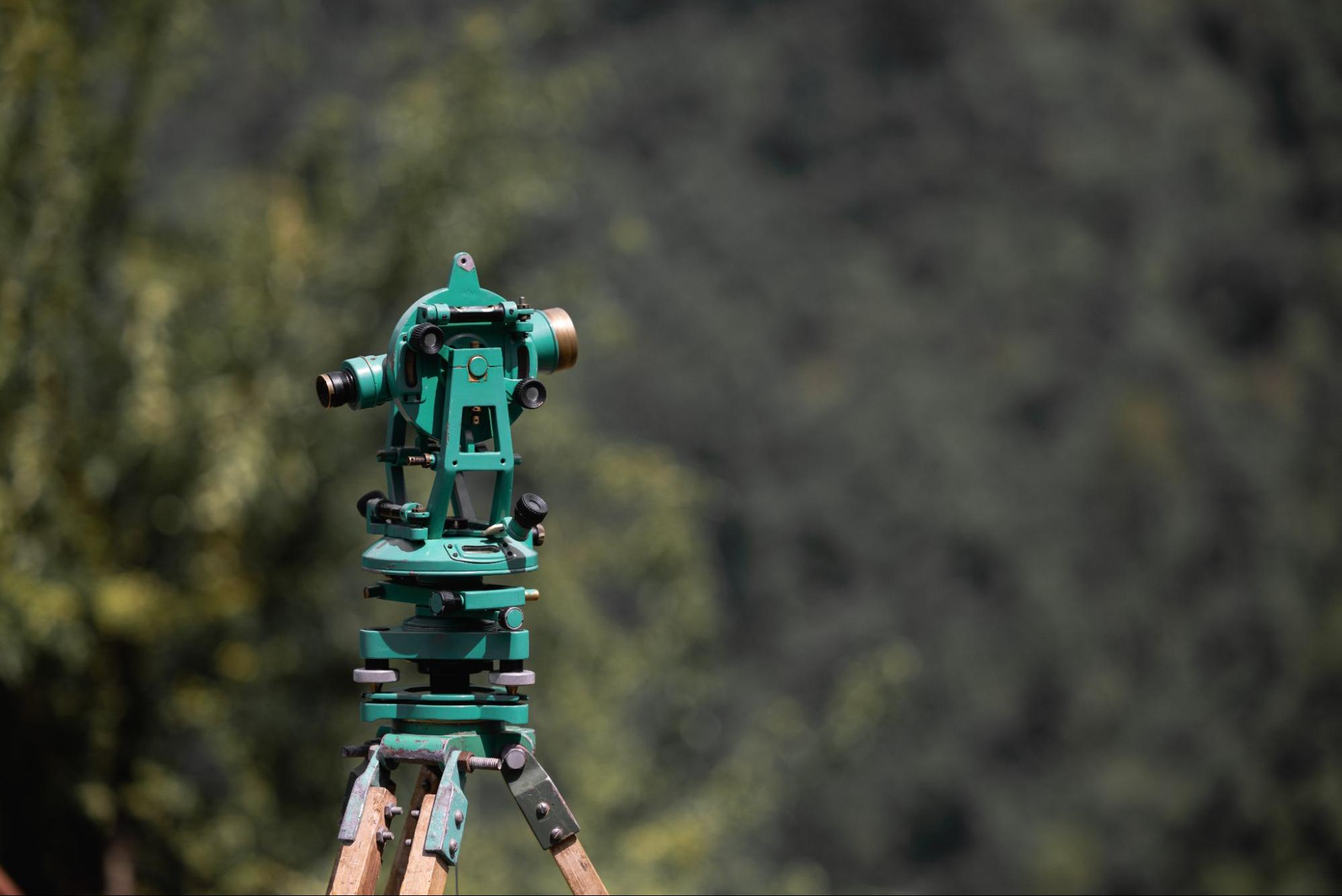 Surveying instrument on tripod used for land surveying services for real estate to measure property boundaries