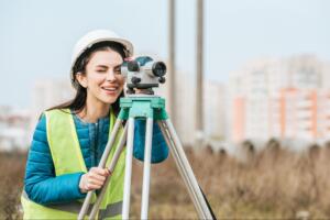 land surveyor using a digital level on a tripod to measure property boundaries after receiving the question how to request for land surveying services