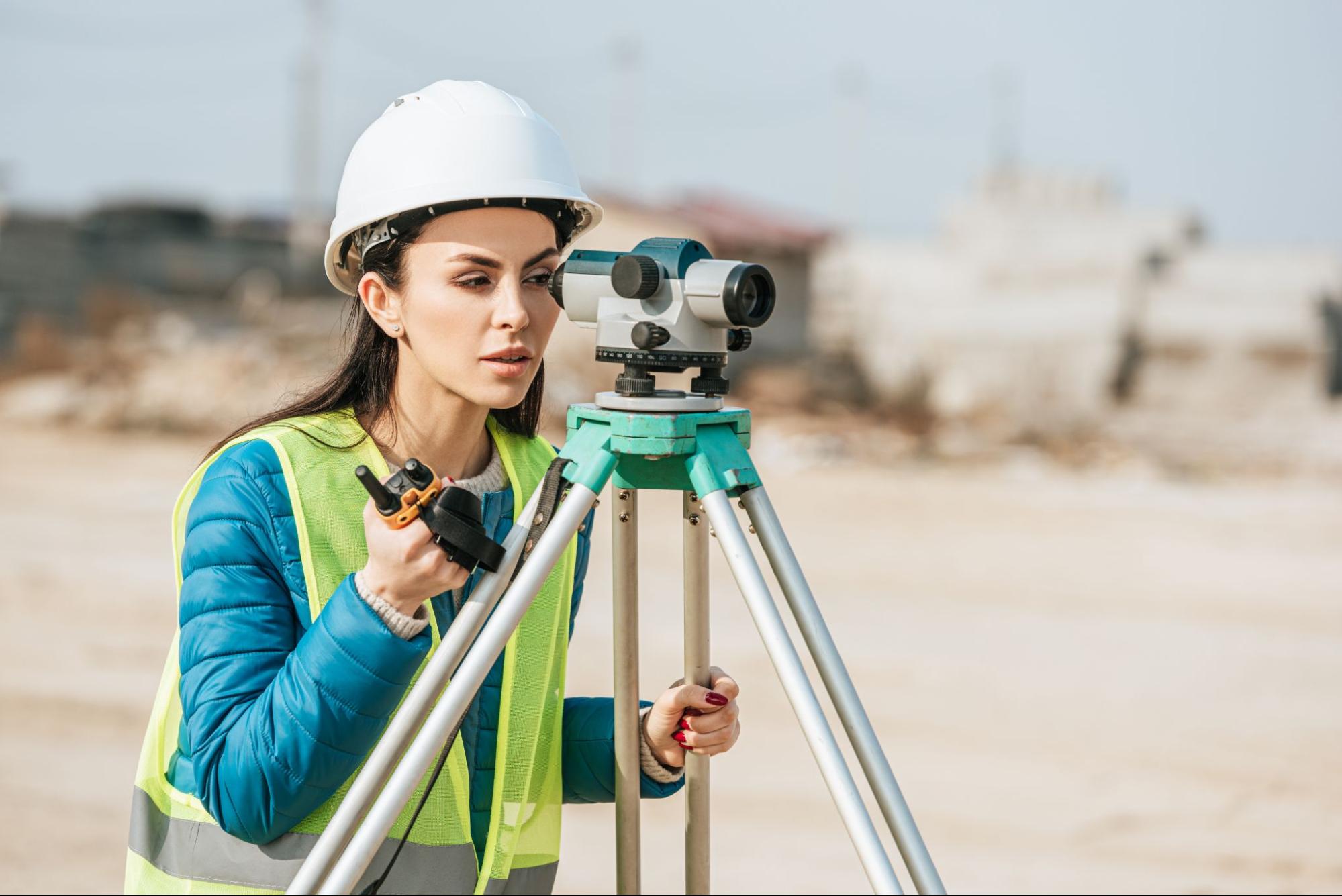 female land surveyor using a tripod level and radio while conducting measurements