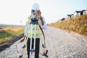 land surveyor using a total station on a tripod to measure property boundaries while preparing a land surveying services quote
