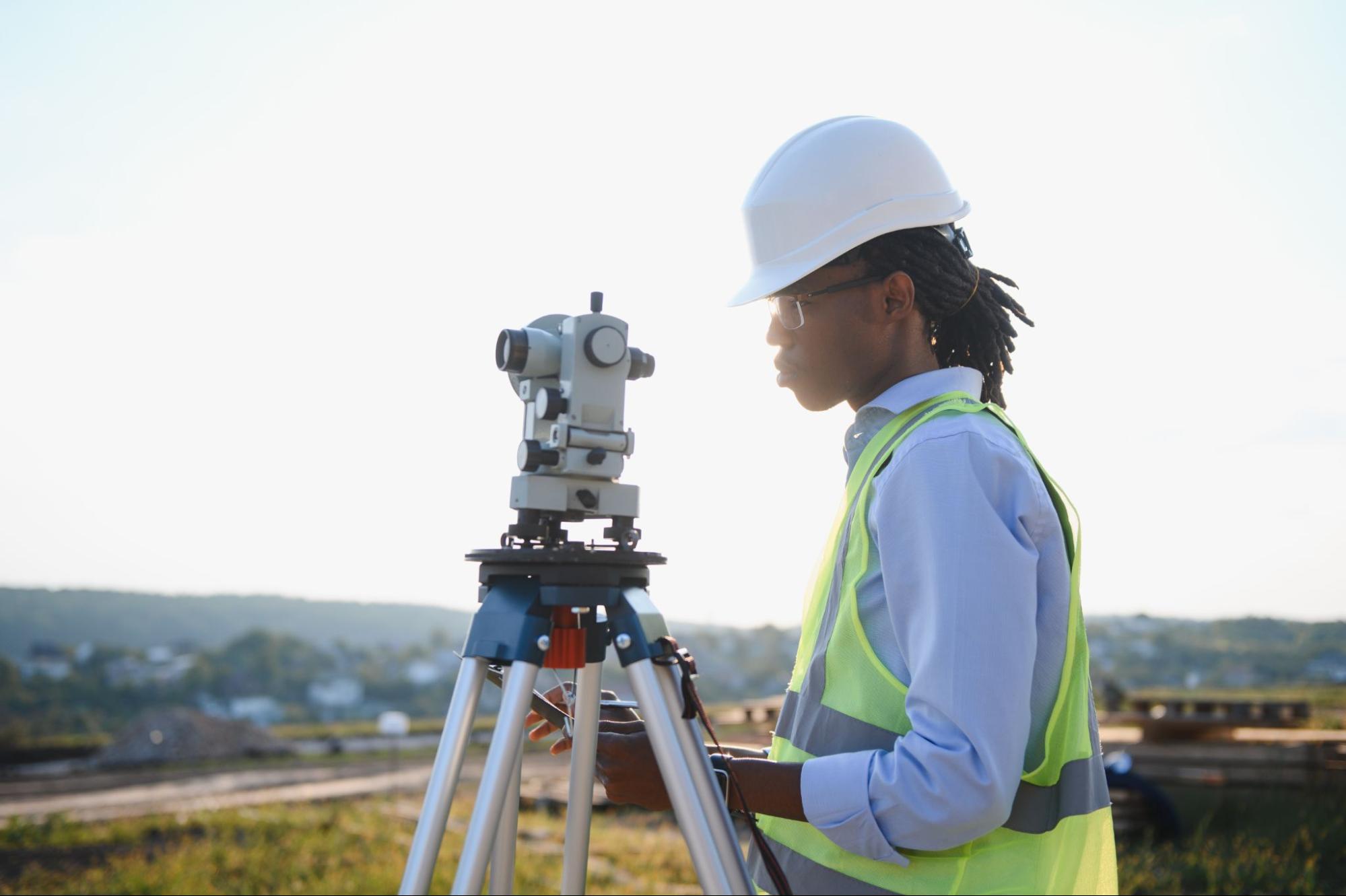 professional surveyor using a tripod level instrument on a job site
