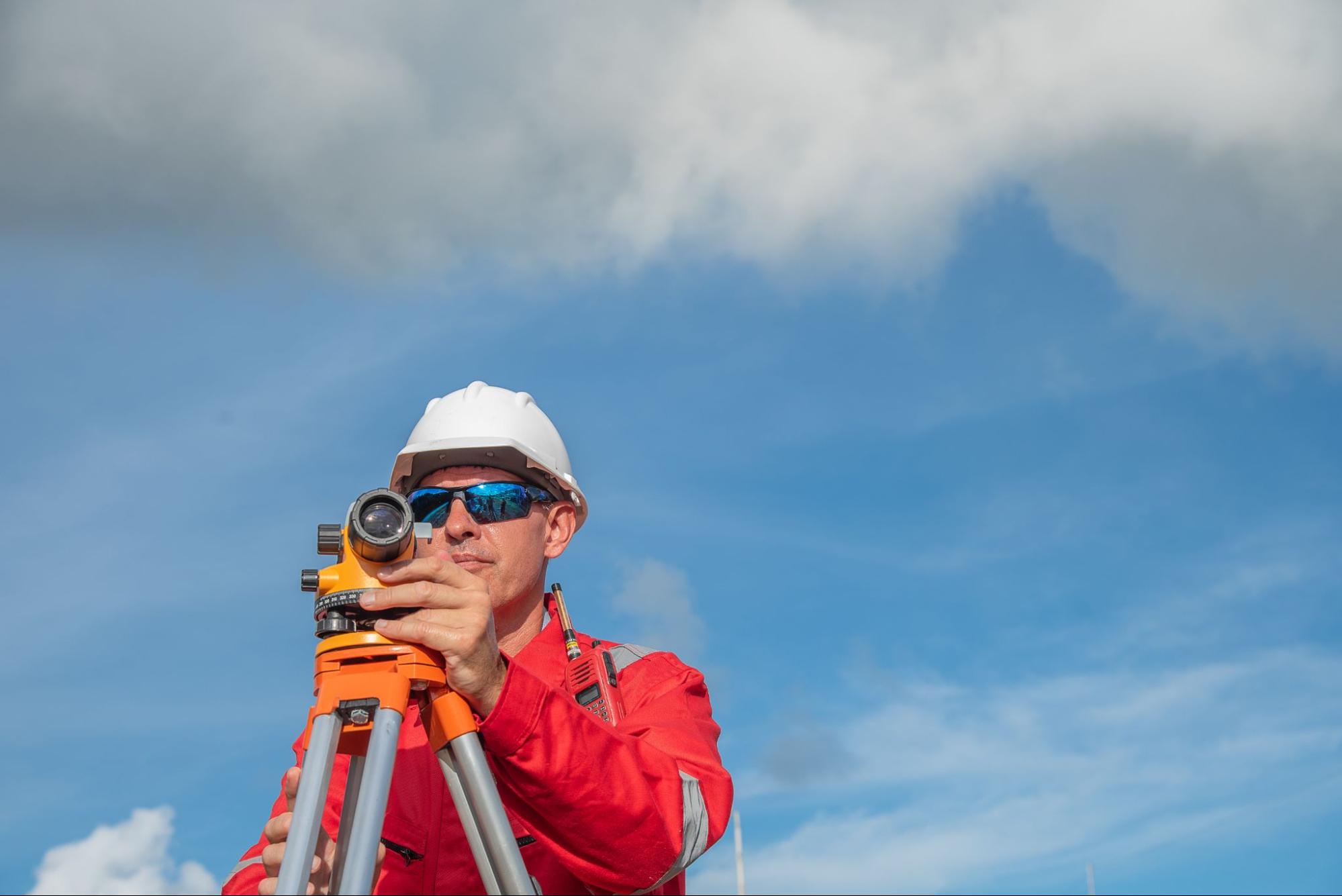 engineer using a theodolite to measure property boundaries for how to book land surveying services guide