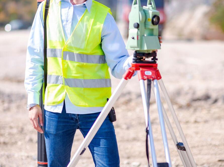 Engineer using tripod survey equipment on a roadside job site