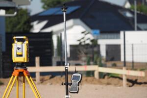 Surveying equipment set up at a residential property to help find a land surveyor for boundary and lot line verification.