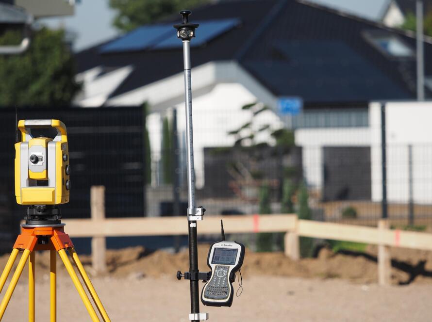 Surveying equipment set up at a residential property to help find a land surveyor for boundary and lot line verification.