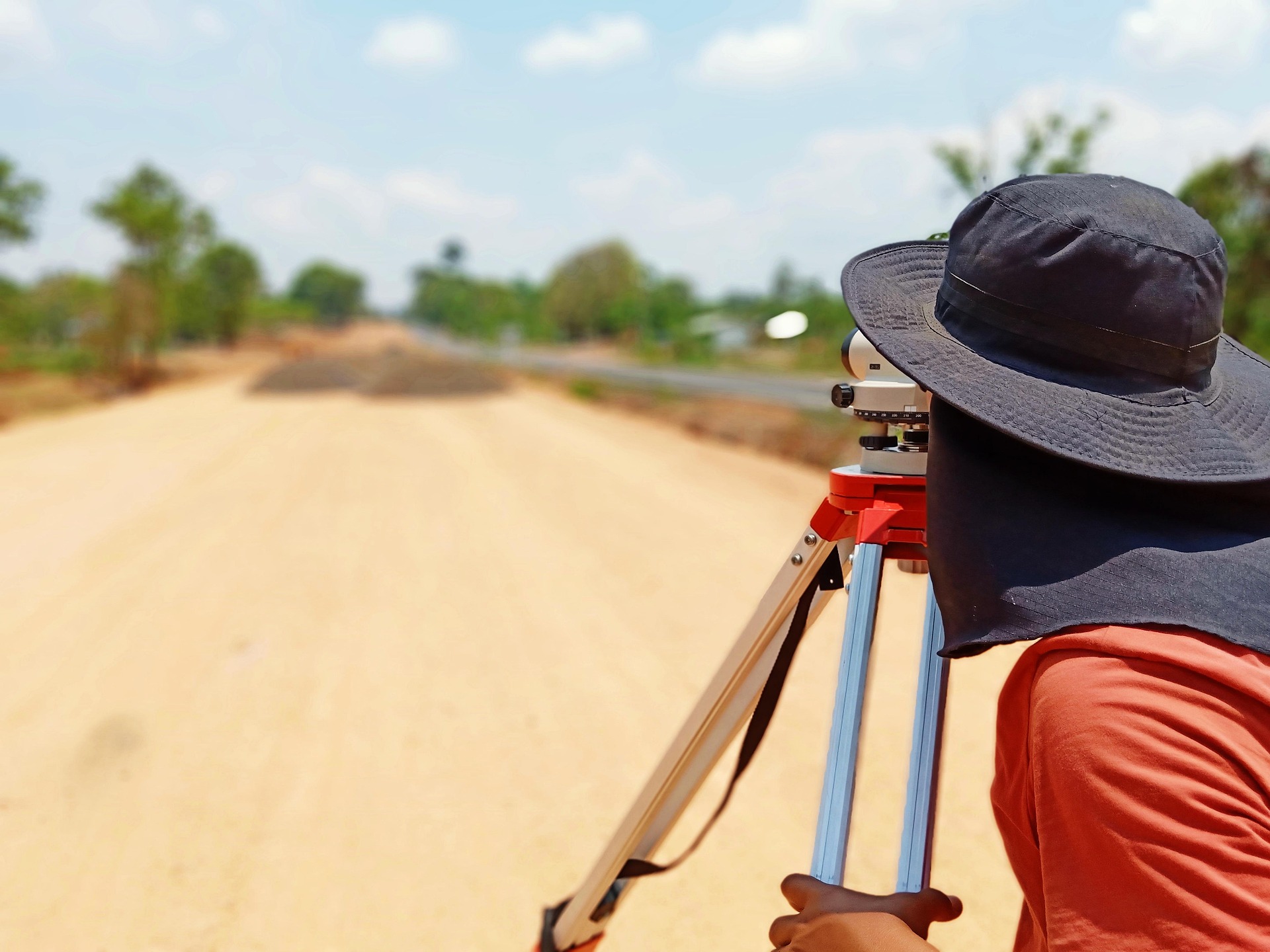 Field surveyor using leveling equipment on a rural road project to find a land surveyor for accurate land measurements.