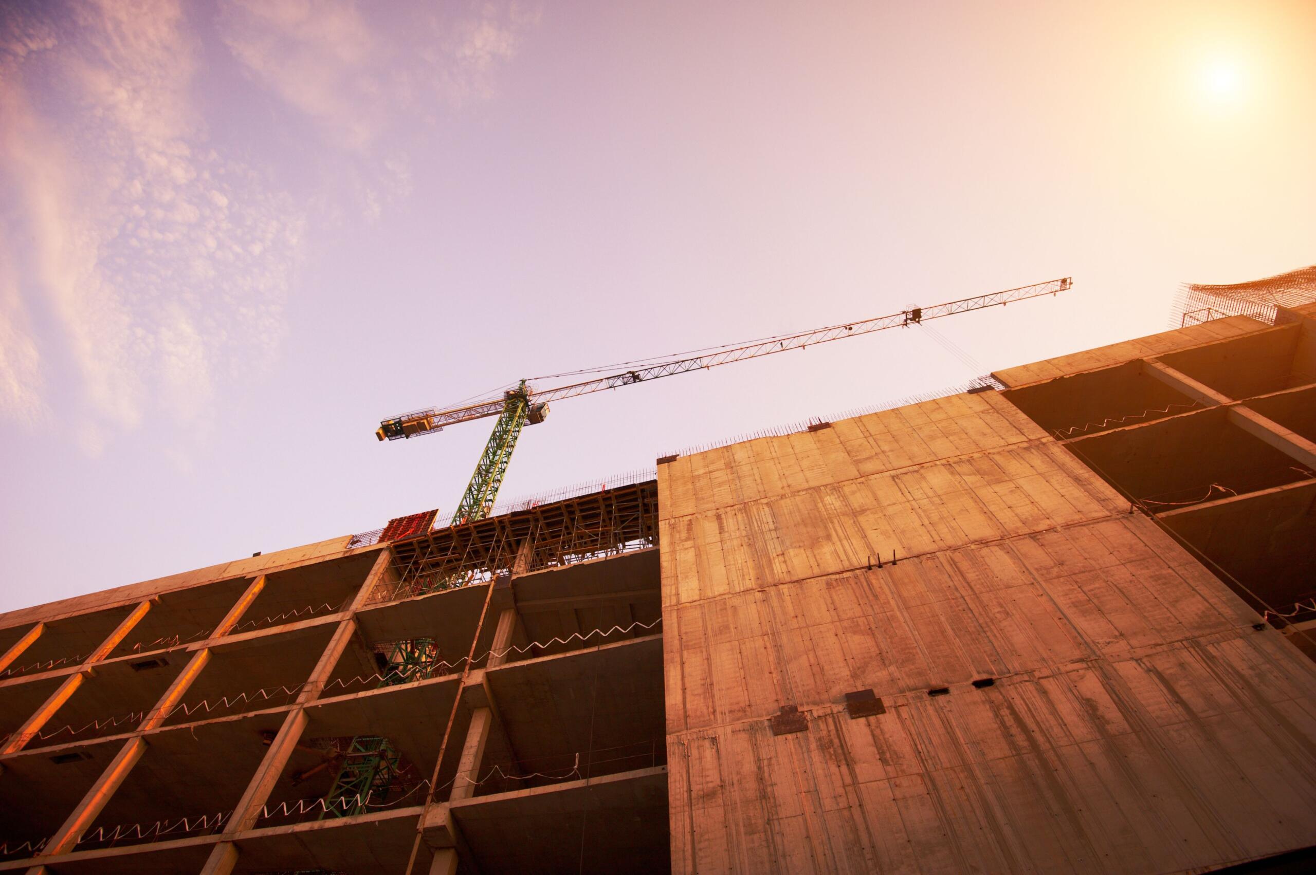 construction of a building by cranes in the afternoon