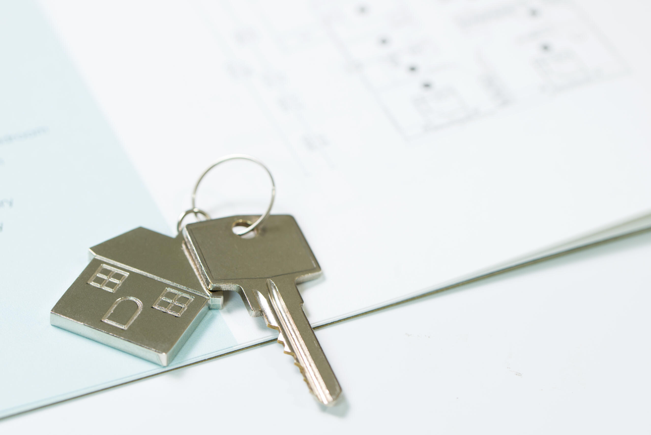House key with house model keychain on house layout plan