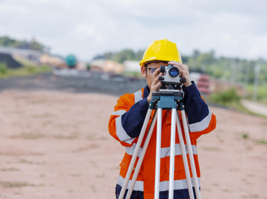 surveyor using leveling instrument representing the need to book professional land surveying services