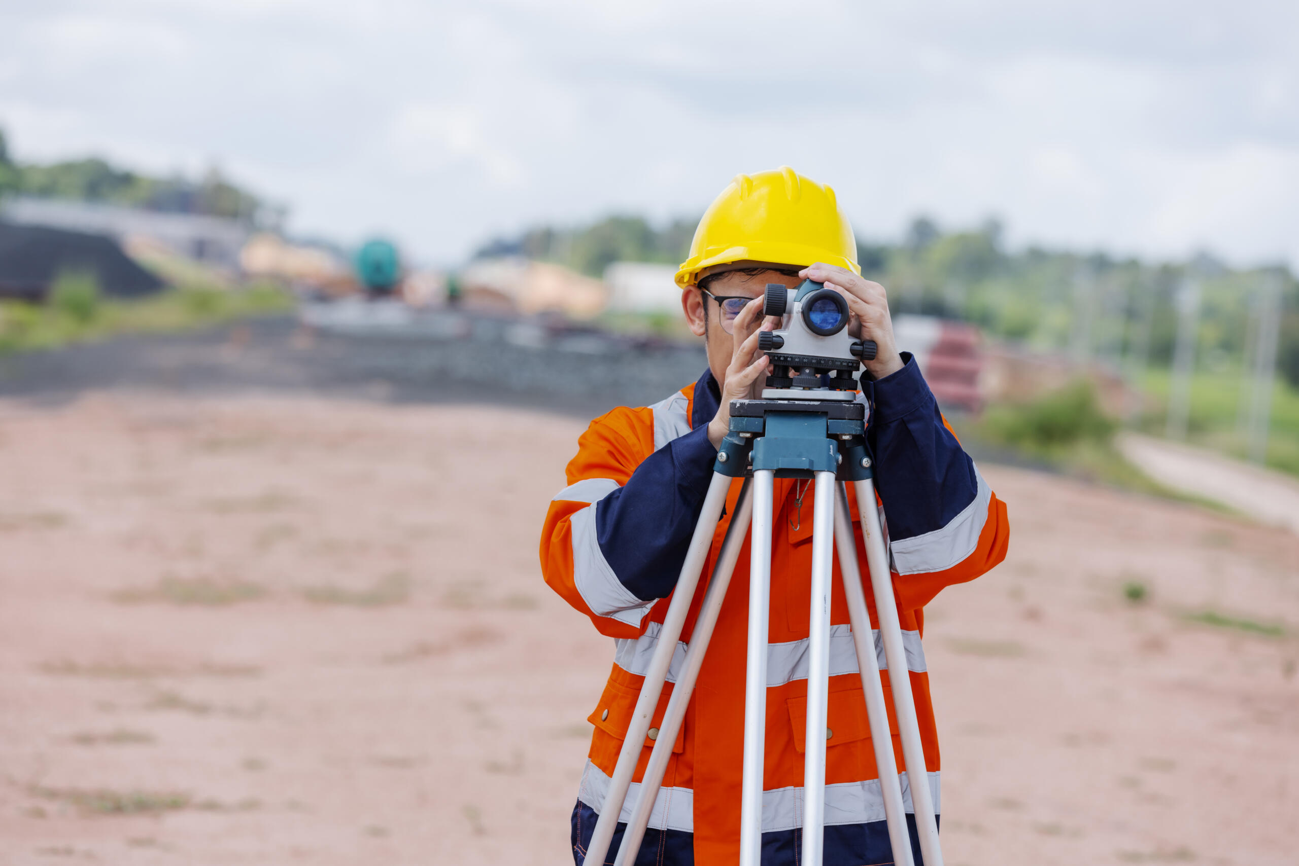 surveyor using leveling instrument representing the need to book professional land surveying services