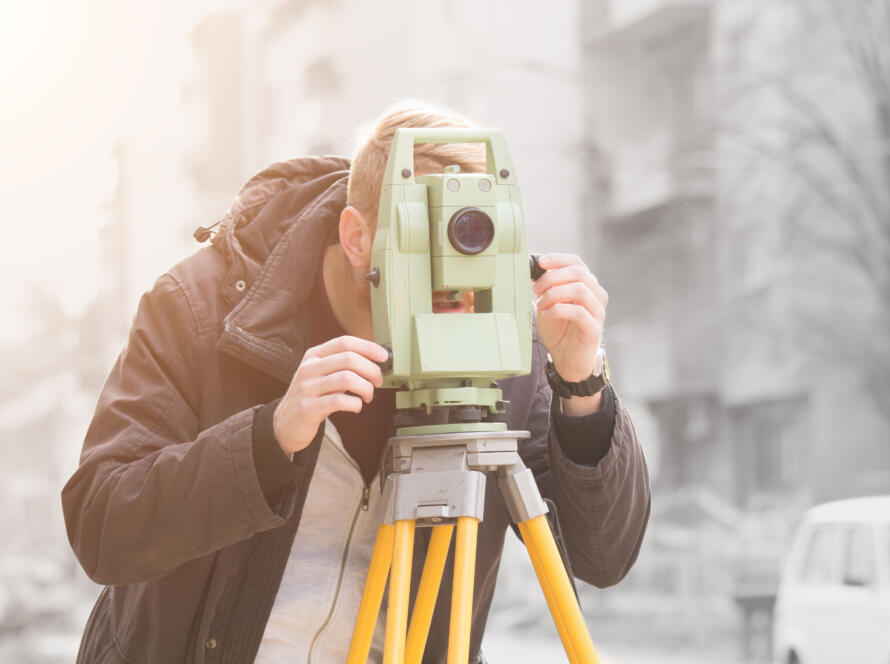 man using level measuring device, representing the need for Land Surveying Services for Home Buyers