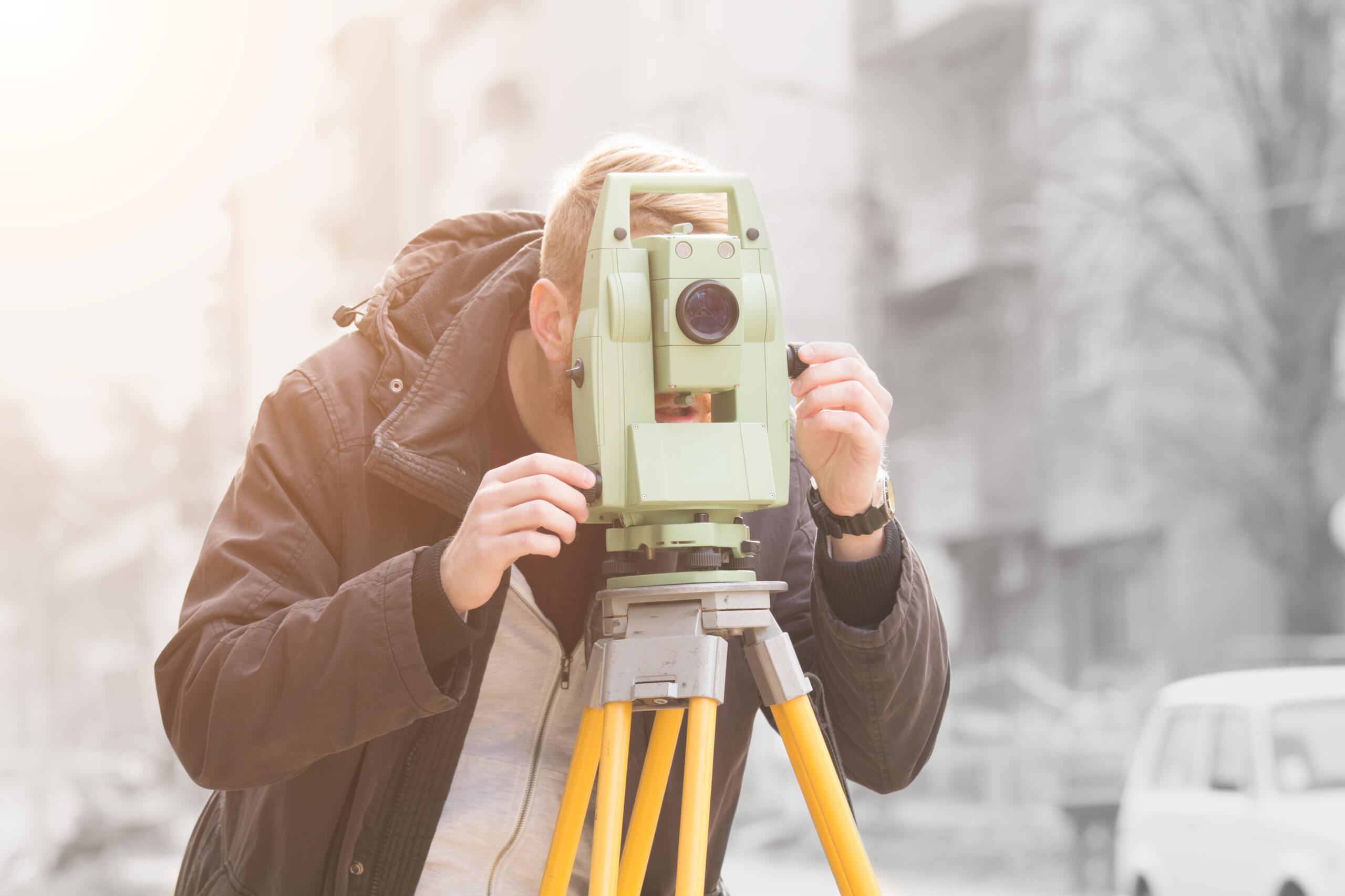 man using level measuring device, representing the need for Land Surveying for Home Buyers