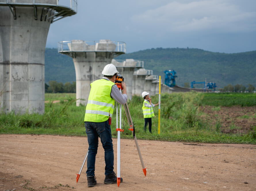Survey team working with a theodolite and road construction plans, representing the need for a Right-of-Way Survey Near Me