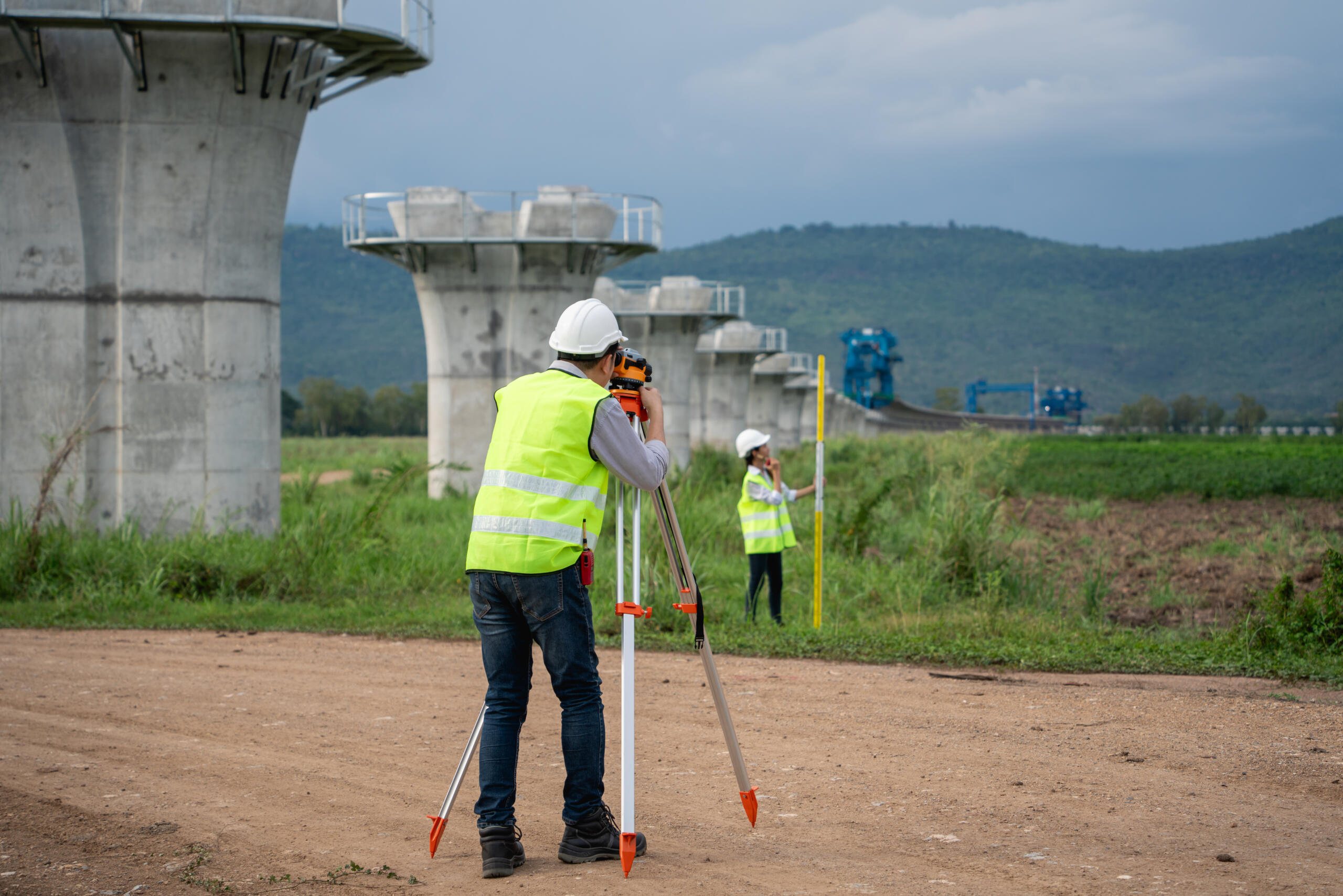 Survey team working with a theodolite and road construction plans, representing the need for a Right-of-Way Survey Near Me