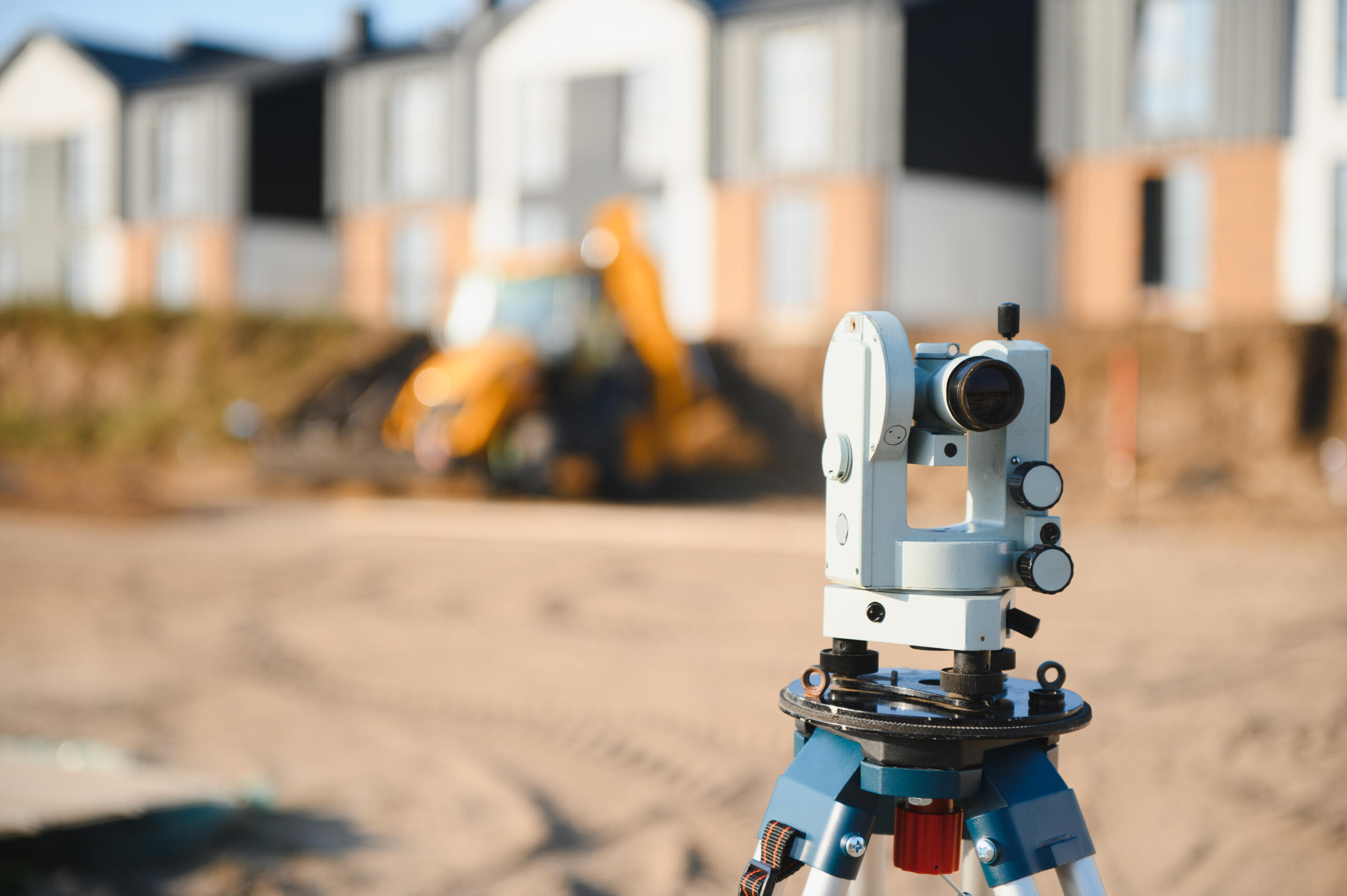 Precision surveying instrument measuring and marking ground at a new housing development, ensuring accurate construction and progress