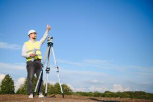 Land surveyor using surveying equipment on a commercial property while preparing a commercial land surveying quote.