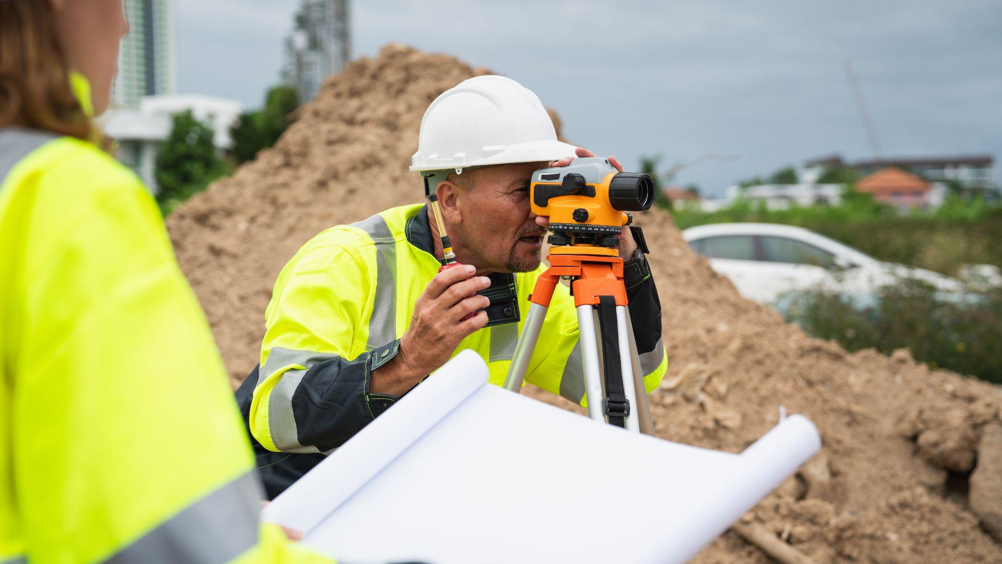 Surveyor using field equipment at a construction site while gathering data for a commercial land surveying quote.