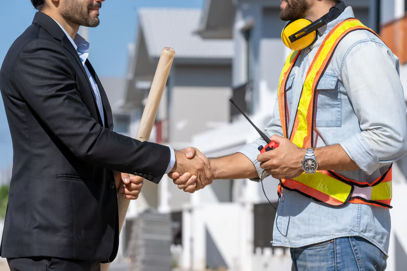 Property owner shaking hands with a land survey professional at a residential development after discussing survey project details.