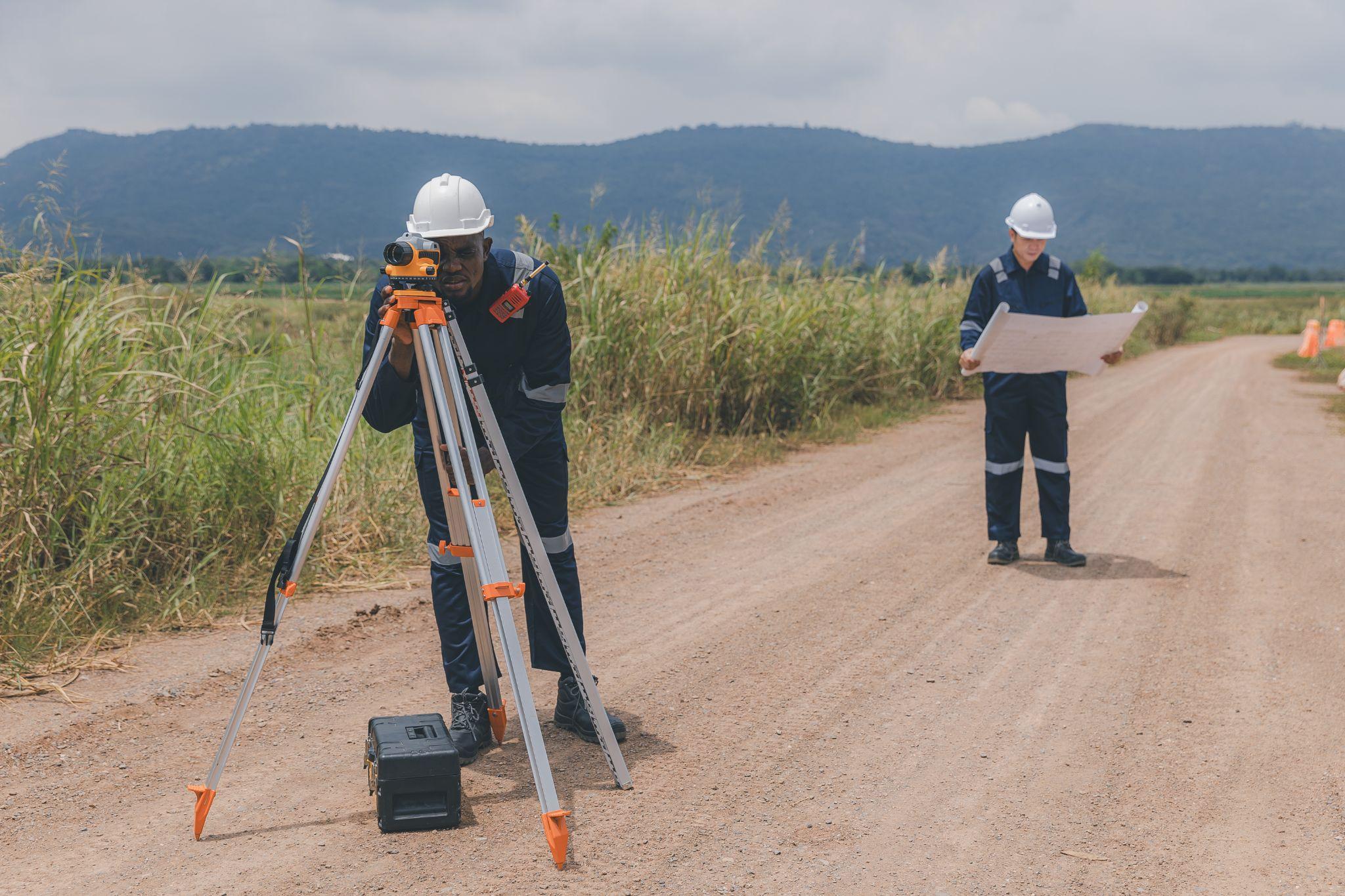 Survey crew taking field measurements and reviewing plans during a property boundary survey