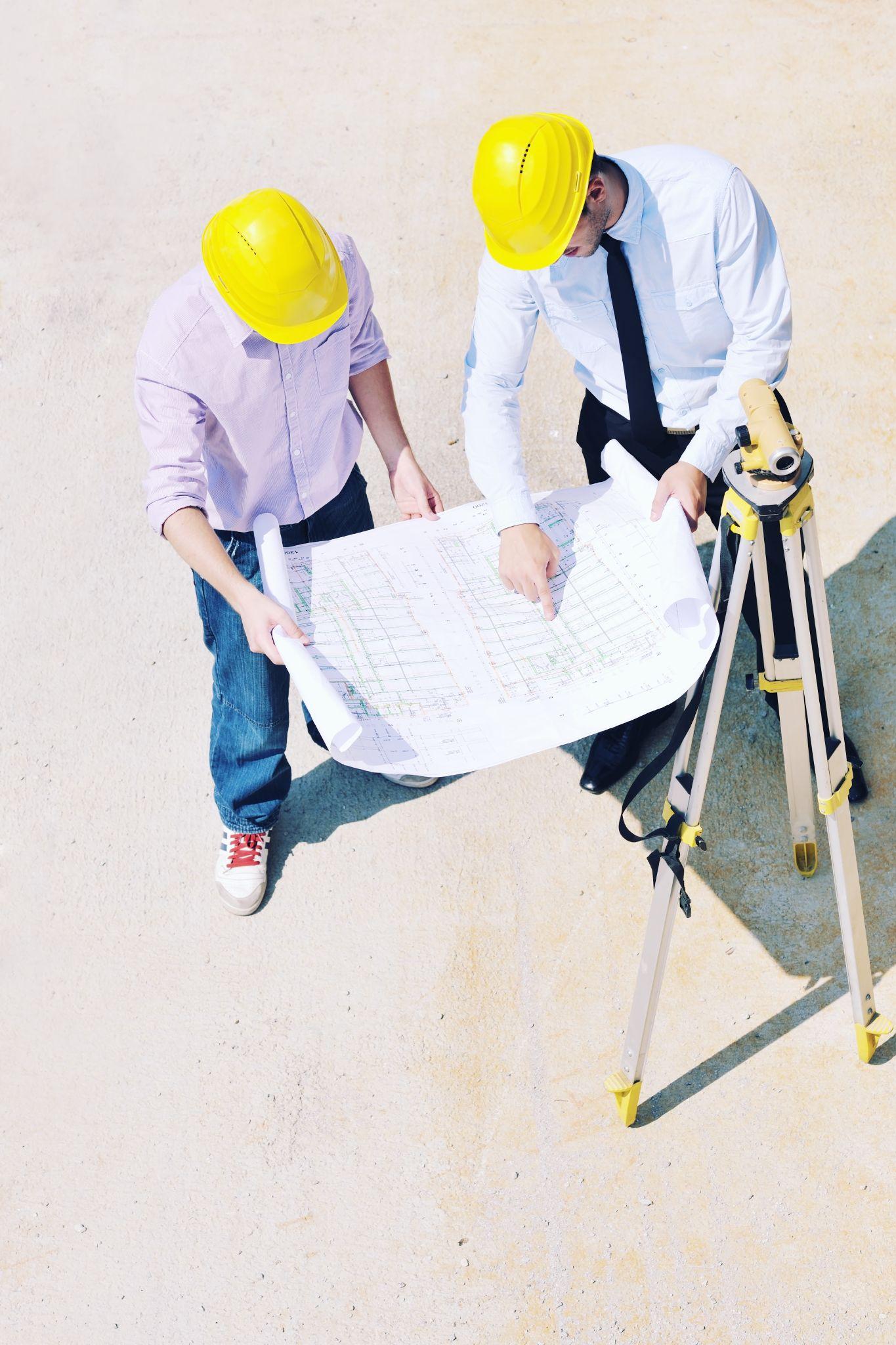 Surveying professionals reviewing property plans and field measurements beside survey equipment