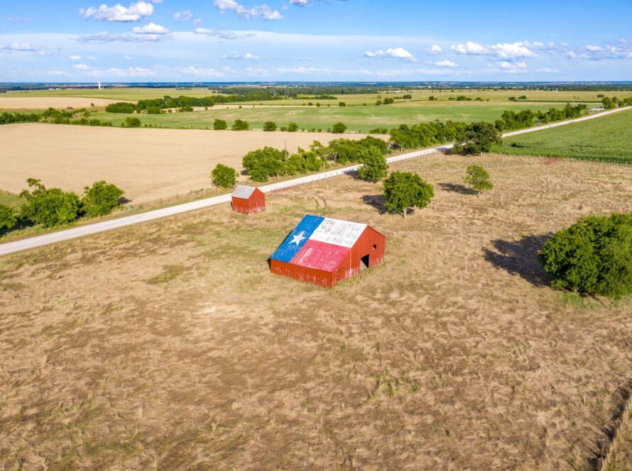 Rural Texas property with farmland and a barn displaying the Texas flag