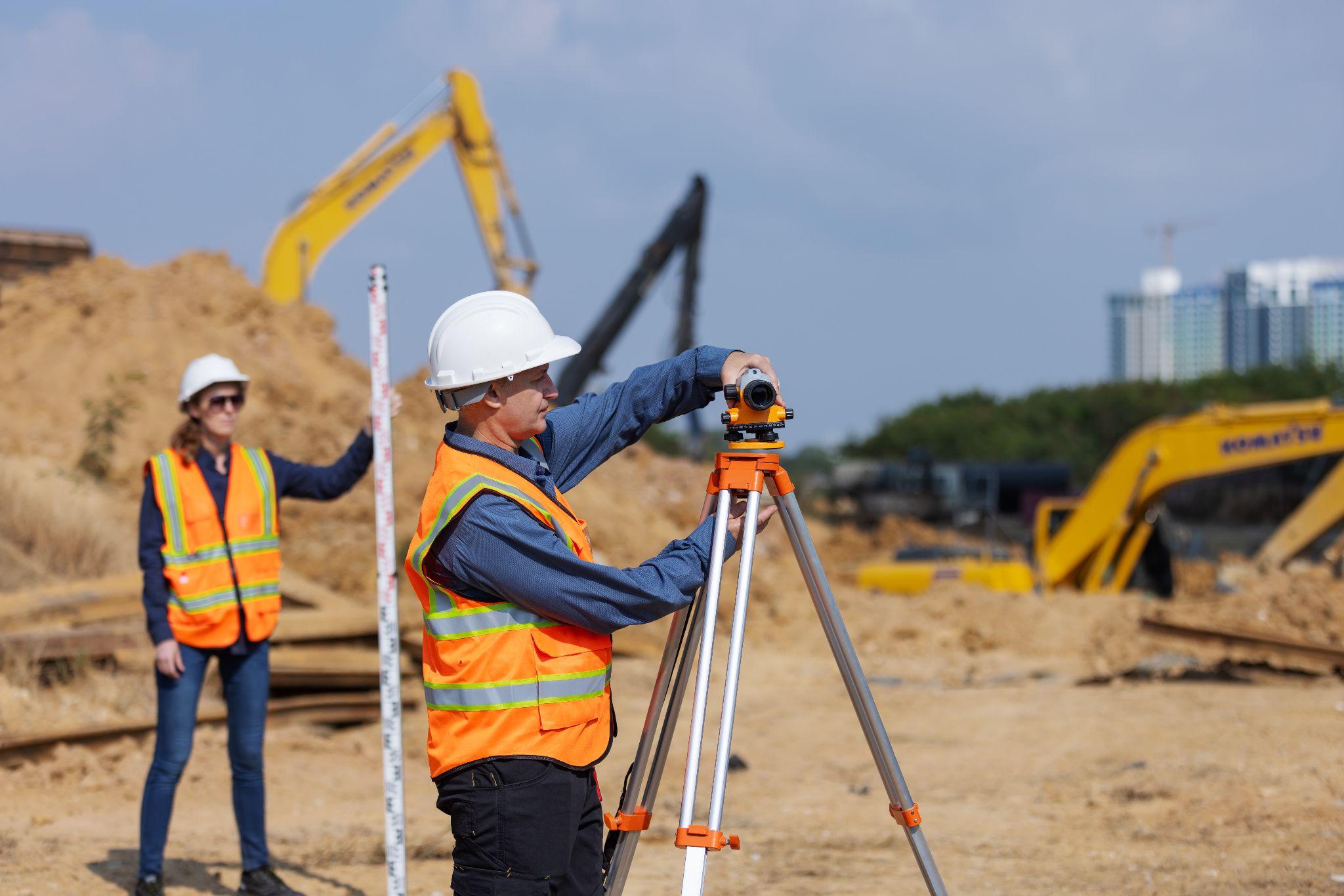 Surveying crew taking measurements at an active construction site