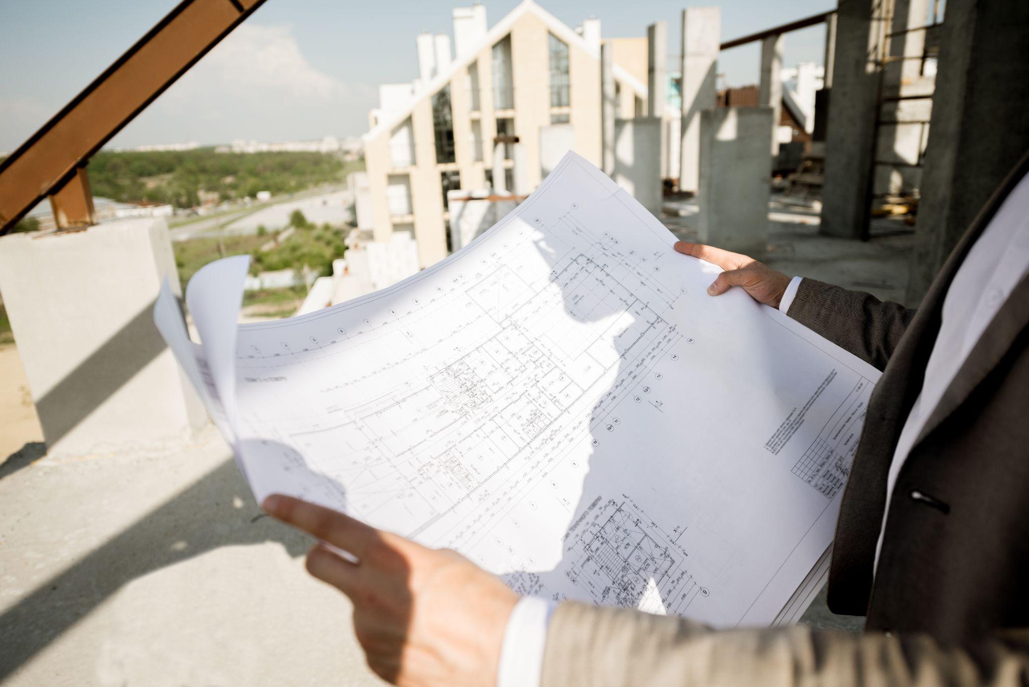 Professional reviewing construction plans while evaluating a development project