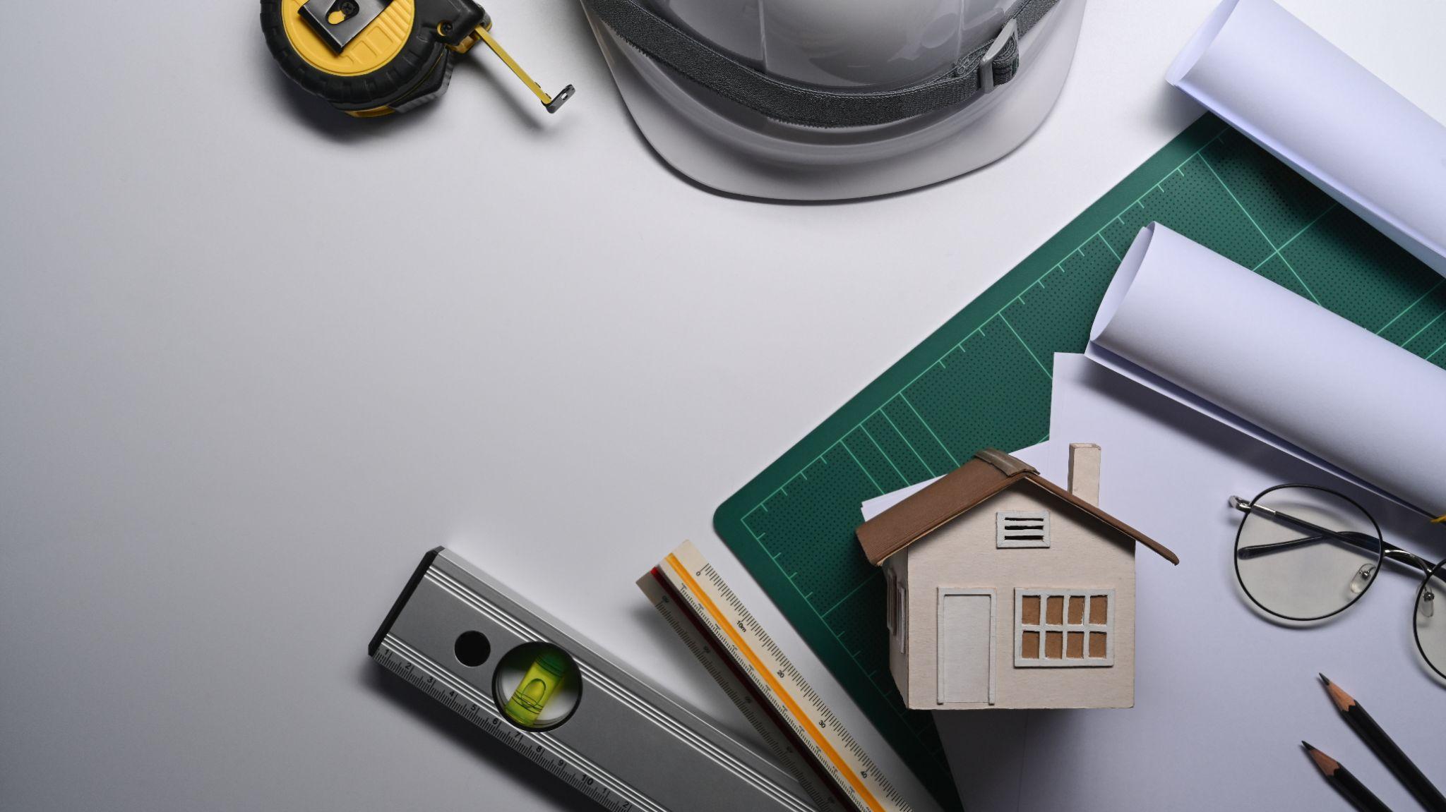 Property plans, measuring tools, and house model used to review survey information