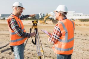 Land surveyors using surveying equipment at an active construction site