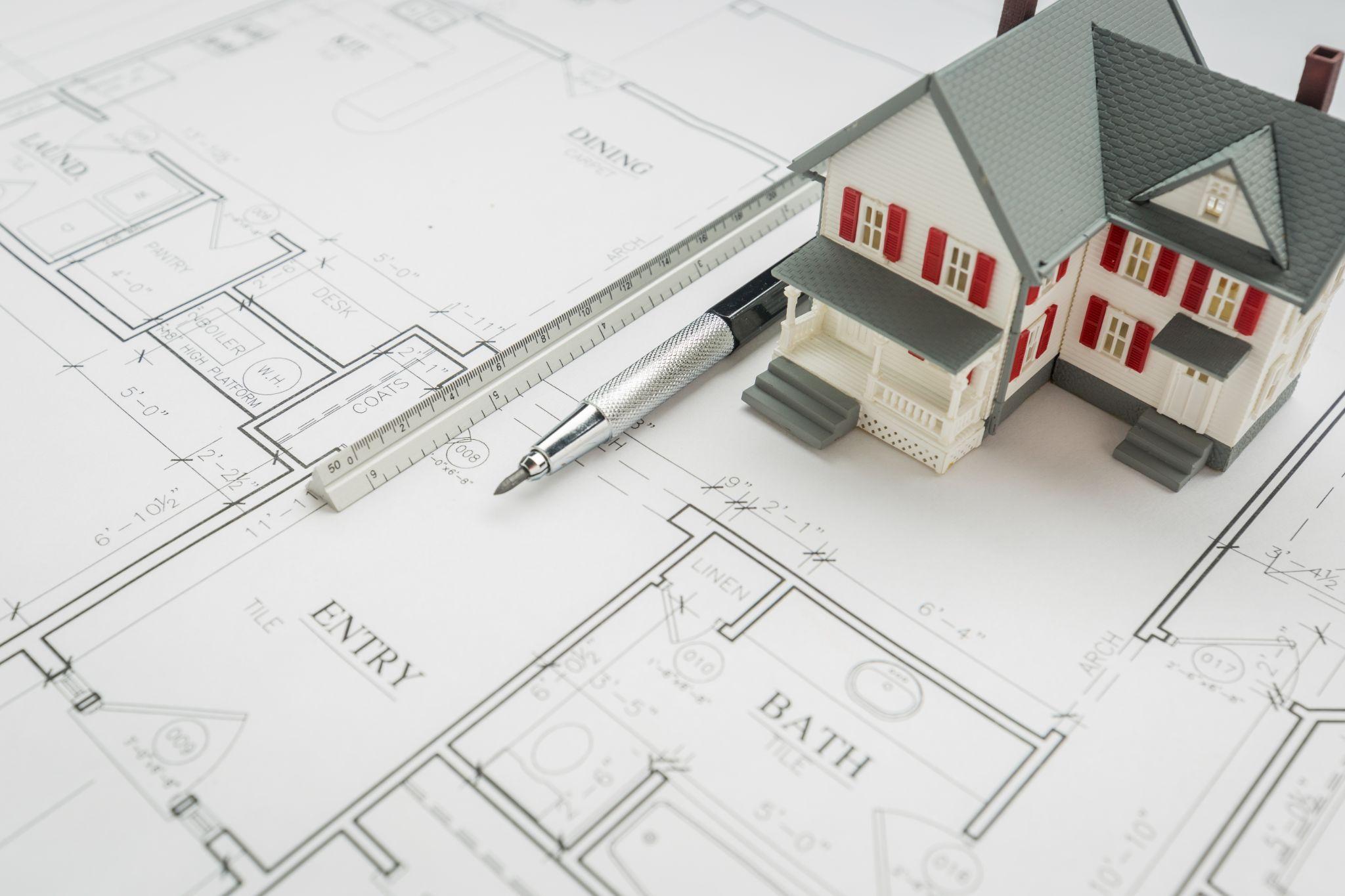 House model and property plans representing land survey needs during a real estate transaction