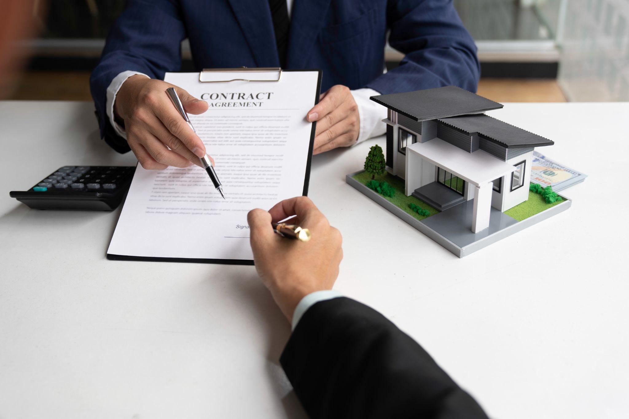 Buyer signing real estate documents beside a model home