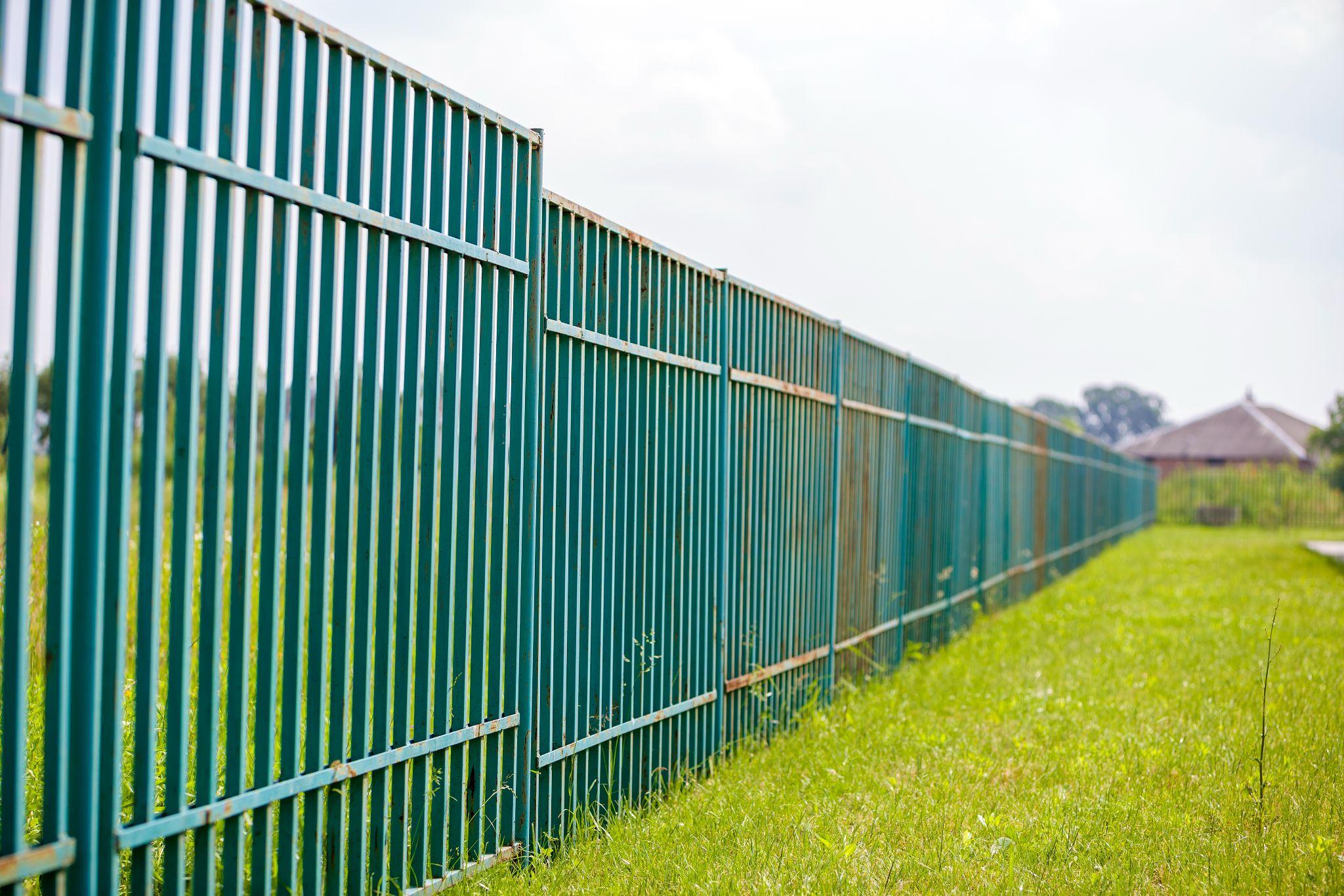 Metal fence running along the edge of a grassy property