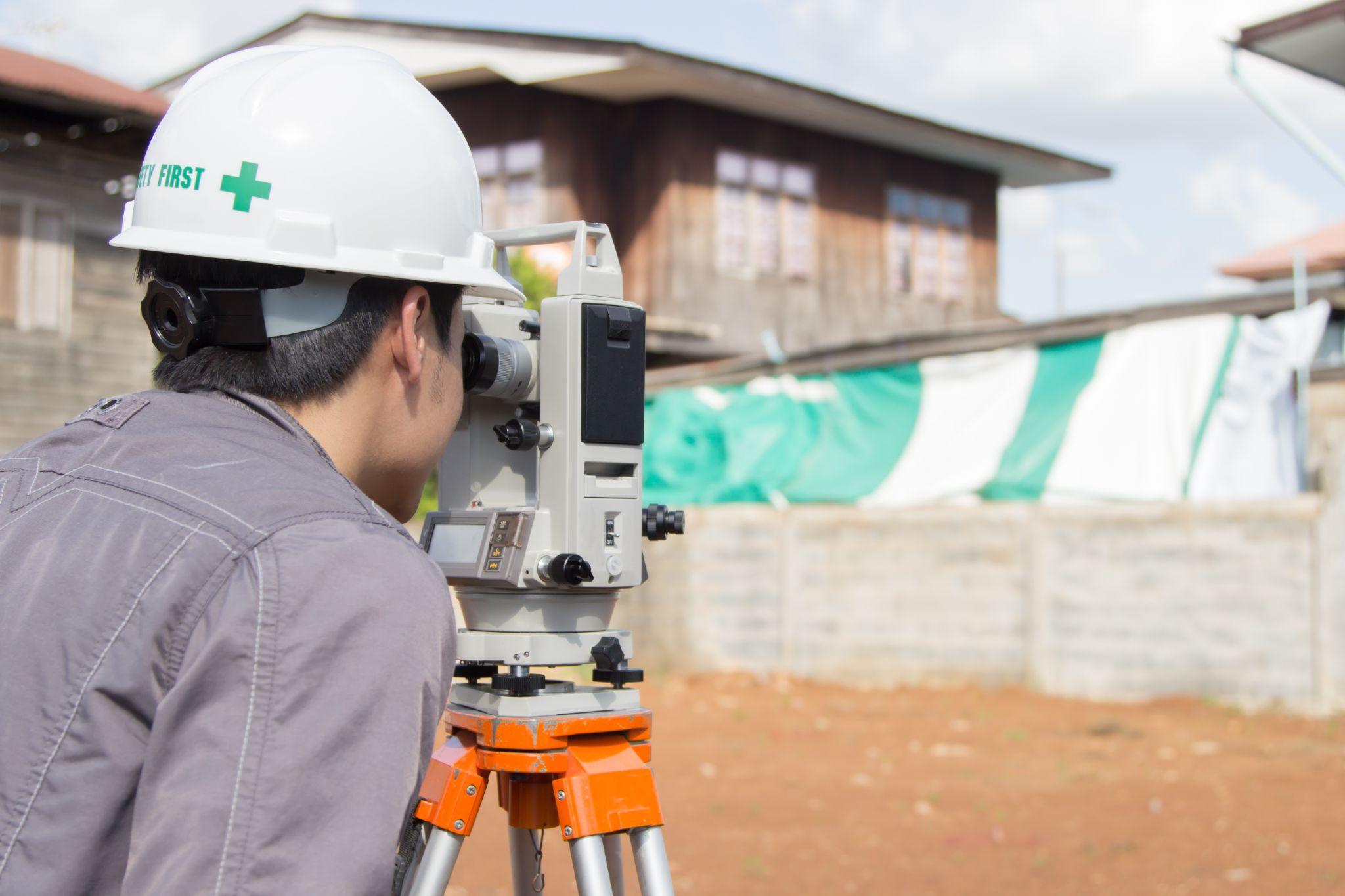 Surveyor using a theodolite to measure a property site
